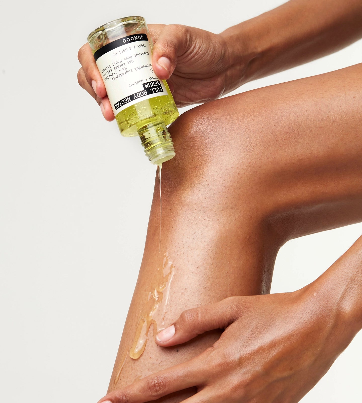 Person applying the Body Serum to their leg with a clear background
