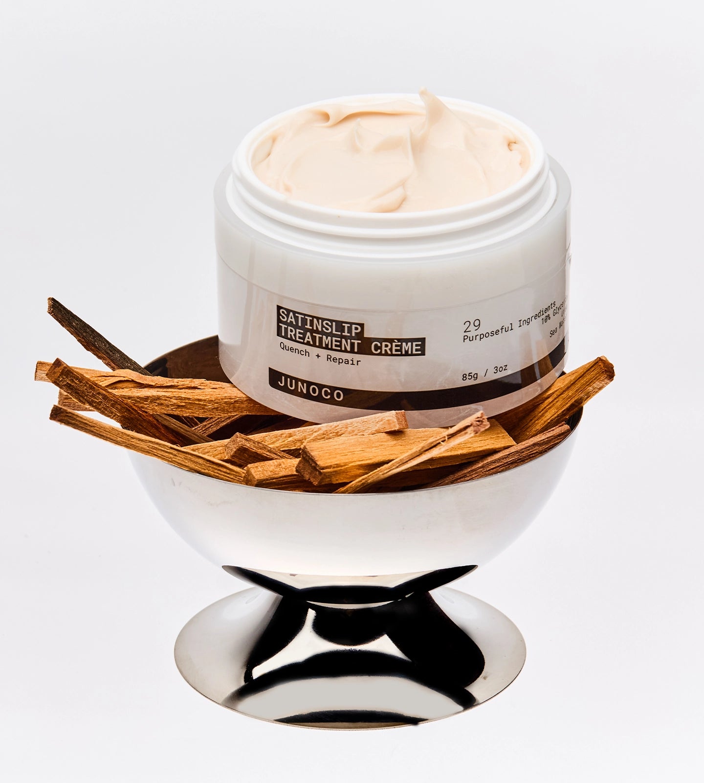 Jar of Junoco SatinLip Treatment Crème with wooden sticks on a white background